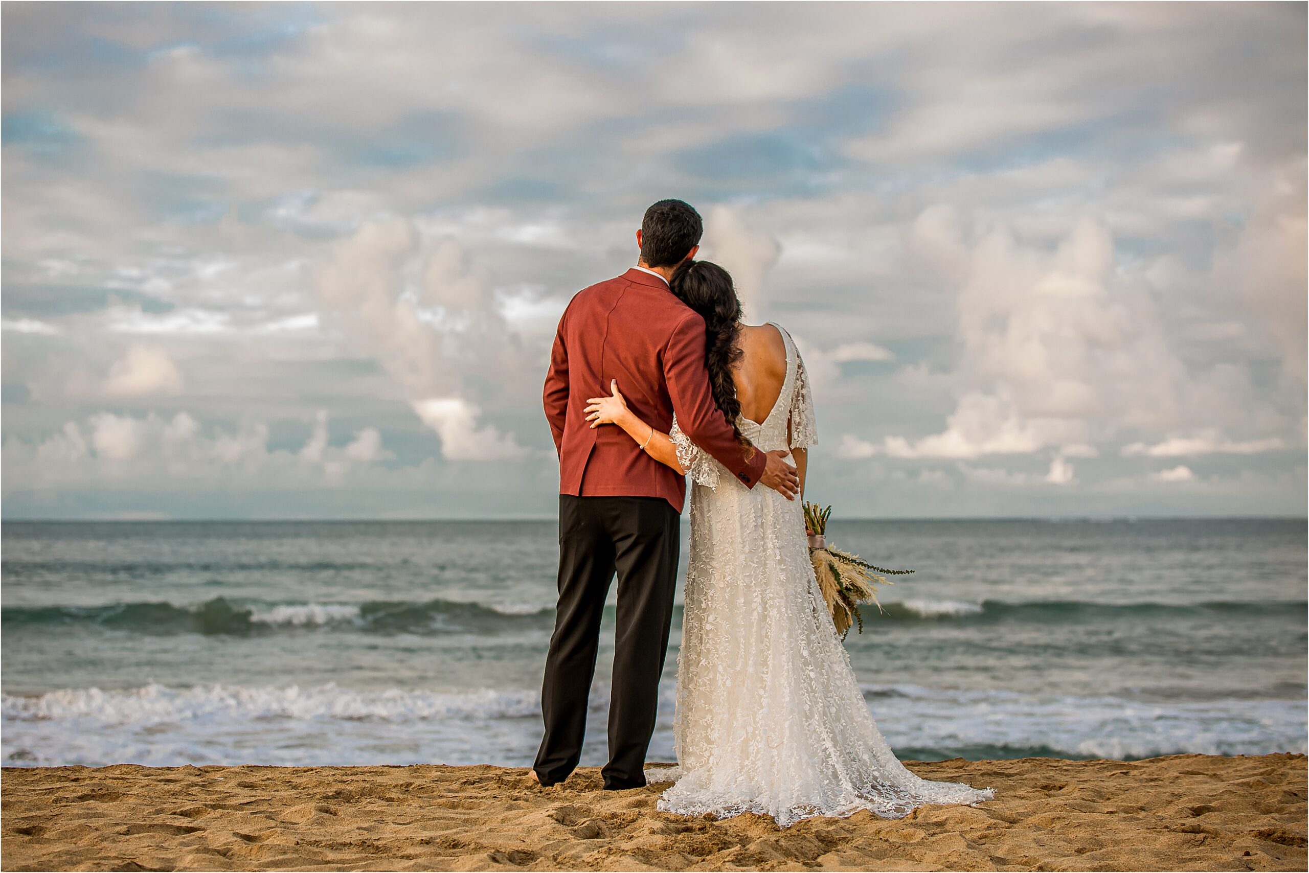 Bride and groom shoulder in shoulder on the beach at sunset for their elopement