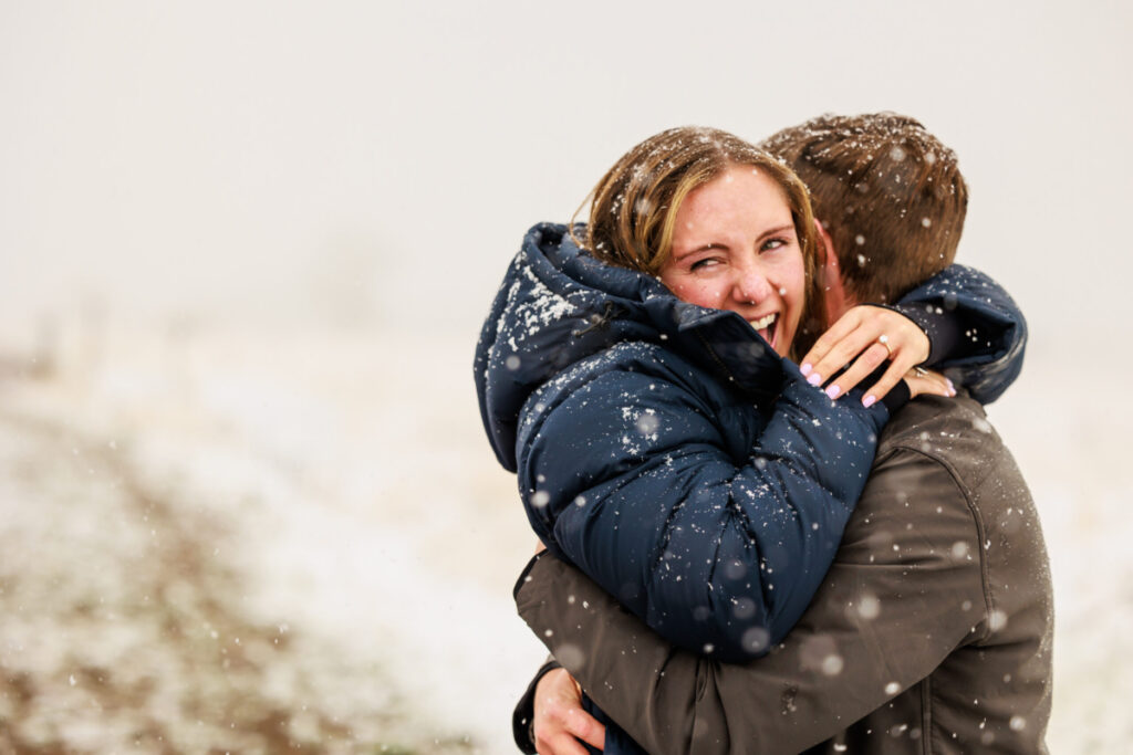 female so excited hugging boyfriend in the snow as he just proposed to her by surprise 