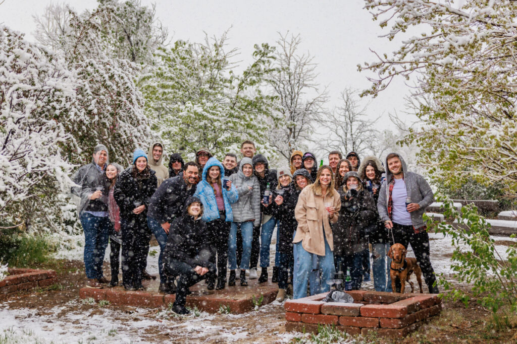 Large group of 20 plus family and friends witnessing surprise proposal in the snow