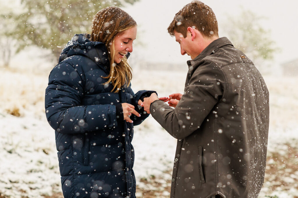 Tyler is putting Andi's engagment ring on in the pouring snow just after their surprise proposal