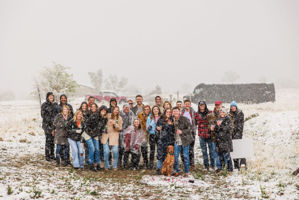 Large group of 20 plus family and friends witnessing surprise proposal in the snow