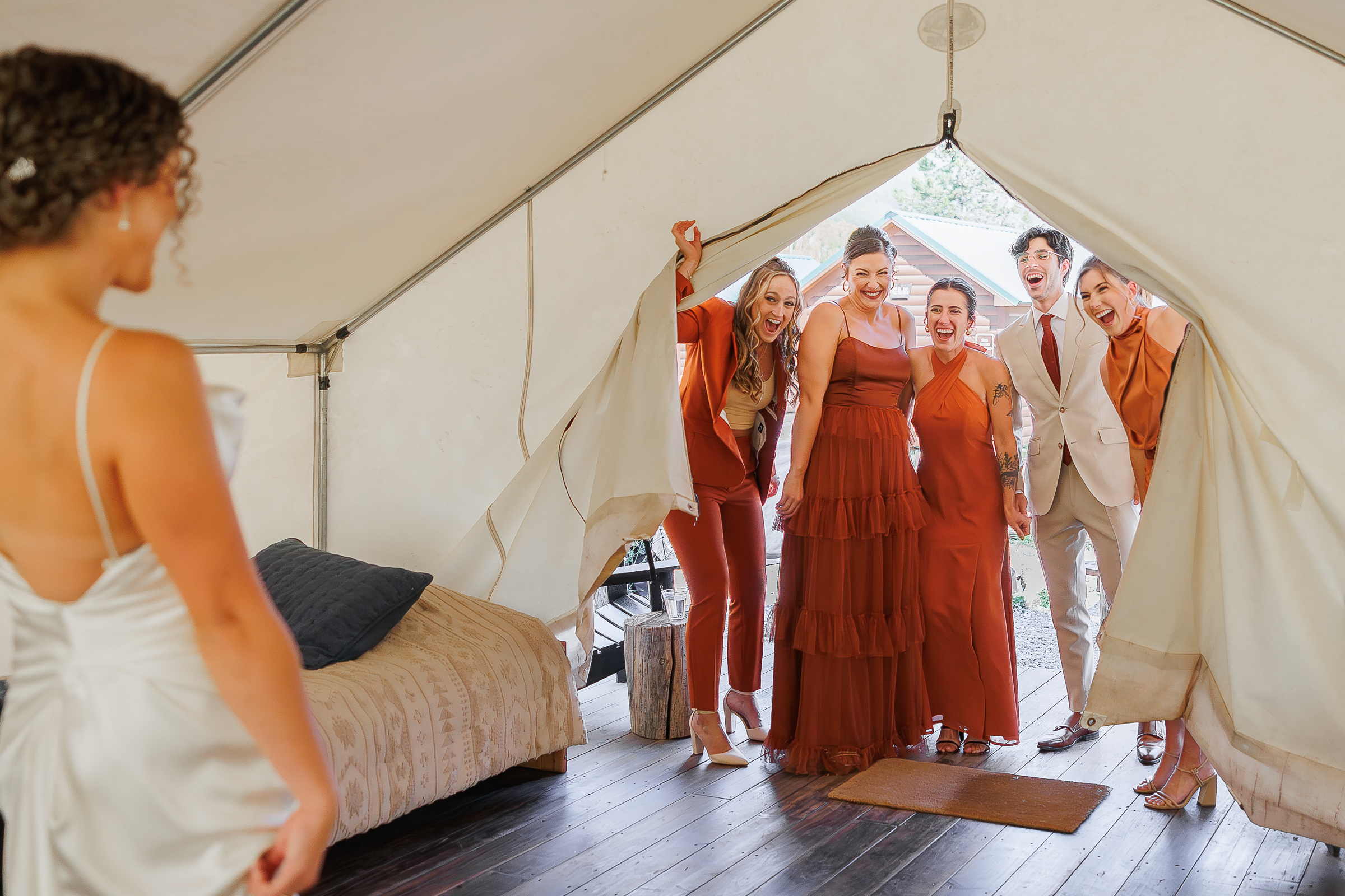 Bride doing her wedding dress reveal with her bridal party whom are all dressed in shades of burnt orange